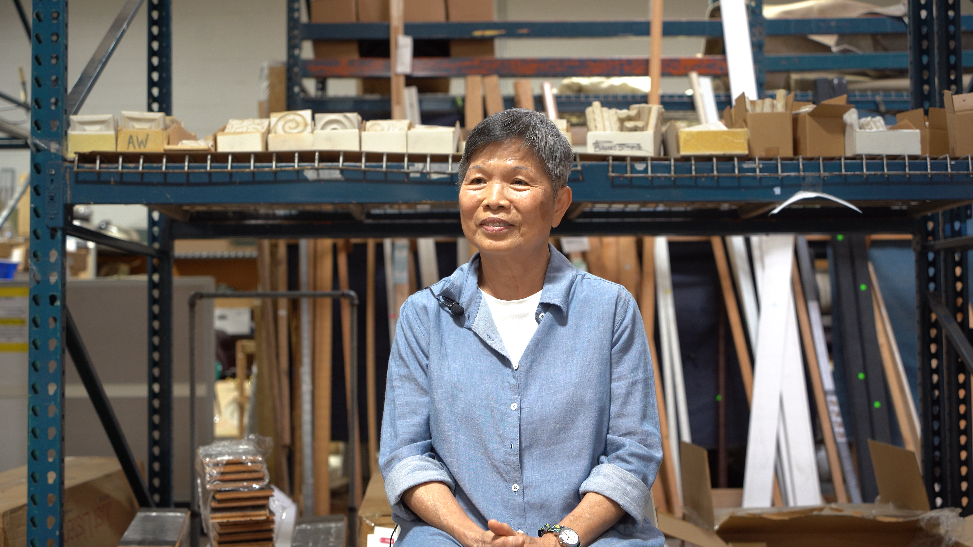 Woman with short hair in front of warehouse shelving and building materials