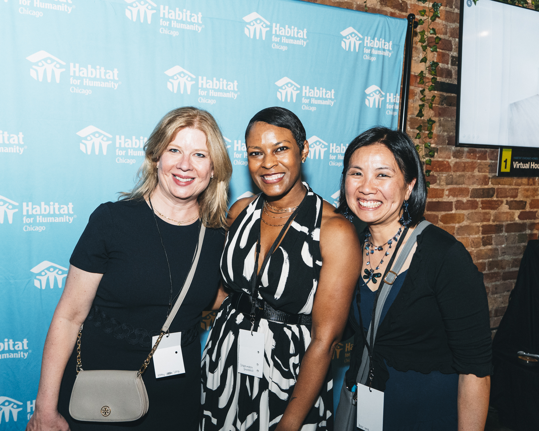 Three women smiling in front of Habitat Chicago backgroun