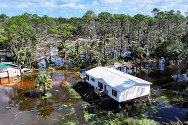 Flooded scene of houses in water and trees in background