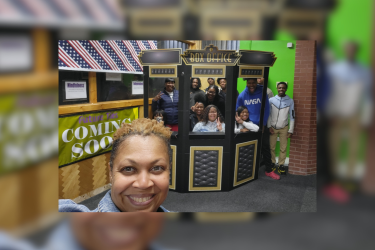 Woman taking a selfie of her and kids in a prop box office